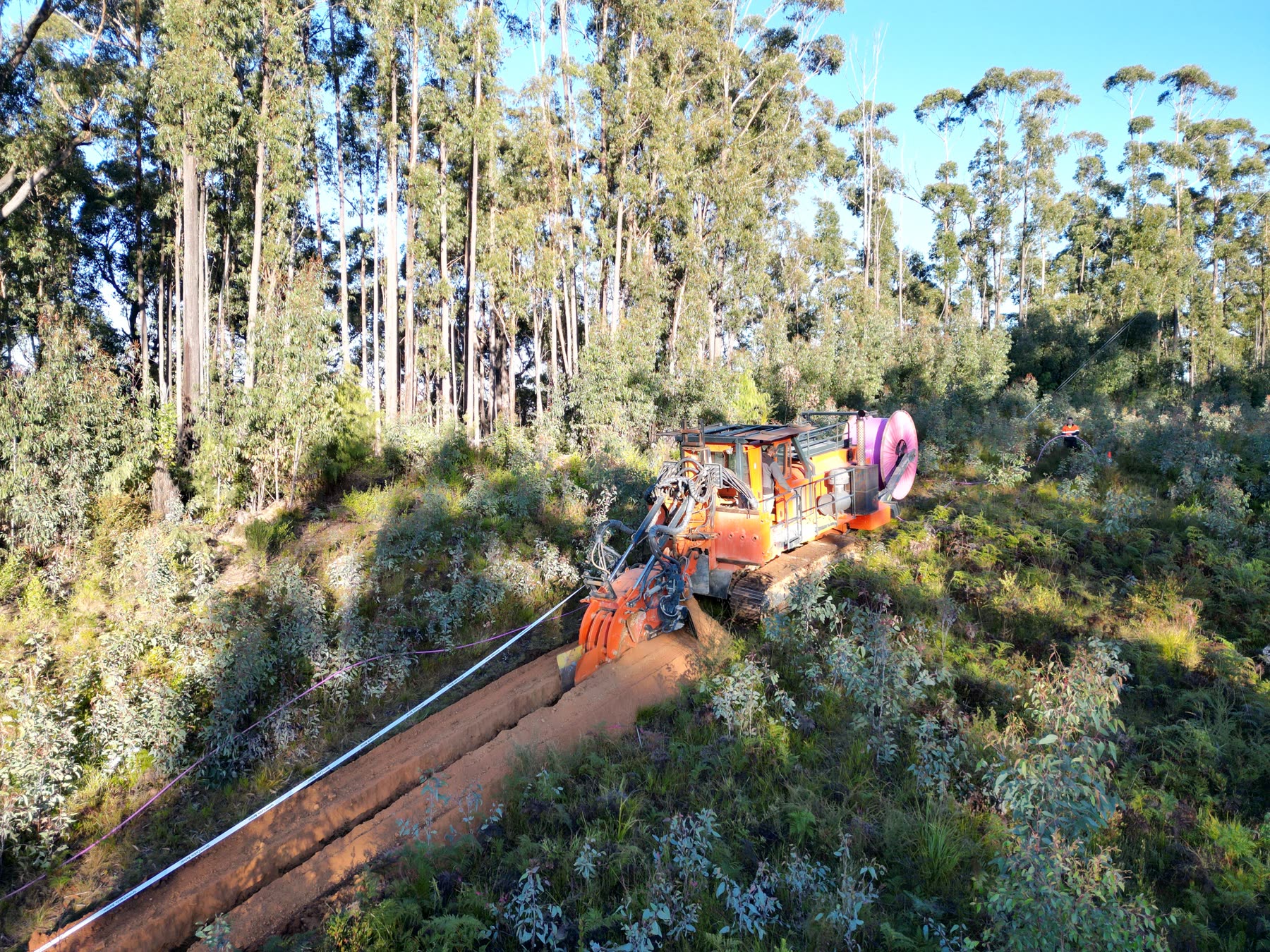 CFH Civils Tesmec chain trencher cutting a deep utility trench through hillside terrain
